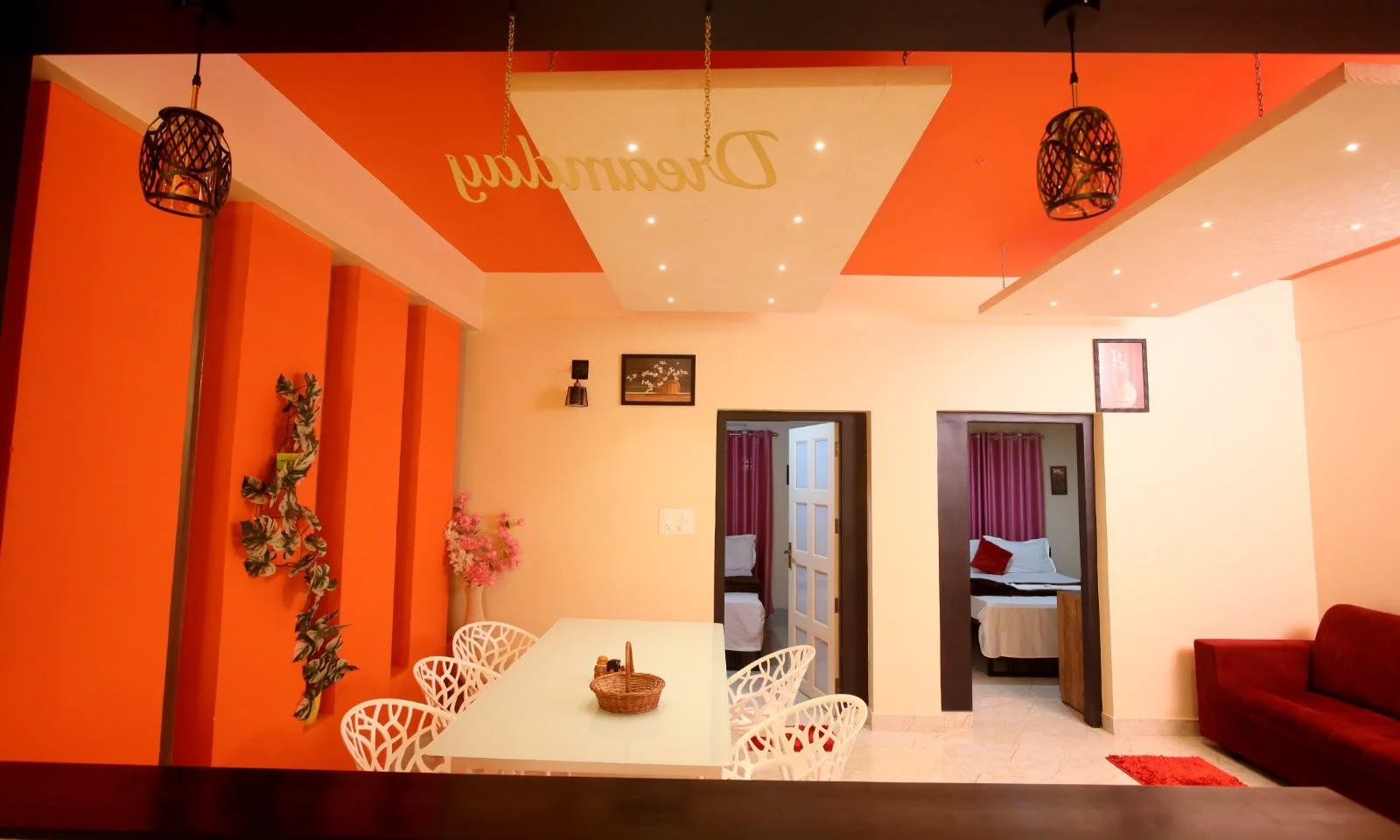 Dining area with an orange feature wall and both bedroom doors